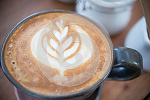 Coffee cup with Latte art on wooden table menu in coffee break time.Latte art froth design pattern is a method of preparing coffee