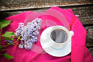 Coffee cup and lilac flowers on wooden background