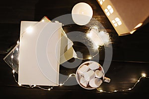 Coffee cup with marshmallows and a book on the table. Still life on dark background, flat lay