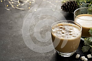 Coffee cup with milk foam and marshmellows, Christmas lights and decorations background. Copy space.
