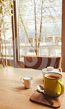 Coffee cup with milk saucer and sugar. Coffee and milk on table in cafe. Energy morning drink. Mug of espresso in restaurant.