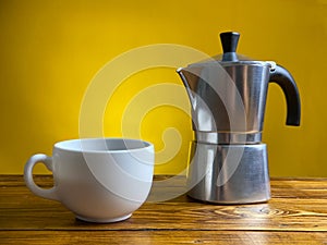 Coffee cup and Moka Pot staying on old wooden table