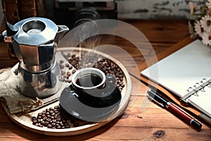 Coffee cup and moka pot on wooden table.