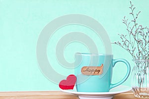 Coffee cup mug with red heart shapeand happy word tag on wooden