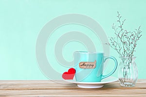 Coffee cup mug with red heart shapeand happy word tag on wooden