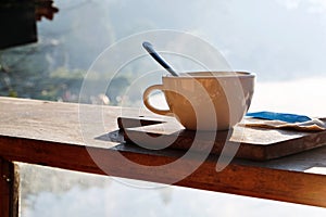 Coffee cup and napkin on wooden table in morning light