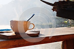 Coffee cup and napkin on wooden table in morning light