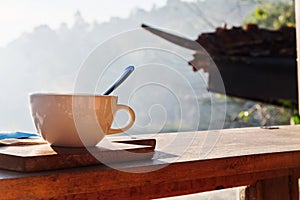 Coffee cup and napkin on wooden table in morning light