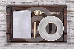 Coffee cup with note book and pencil on a tray on white wooden table. Lifestyle concept