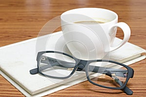 Coffee cup and notebook with glasses photo