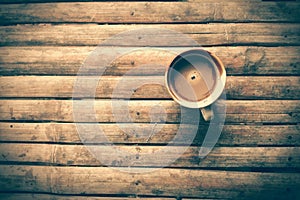 Coffee cup on old bamboo table top with vintage tone processed
