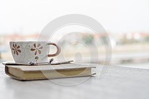 Coffee cup and old book on wooden table.