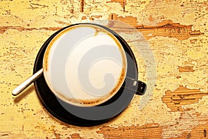 Coffee cup on old wooden pastel yellow table background.