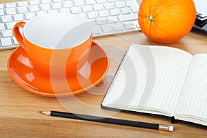 Coffee cup, orange fruit and office supplies