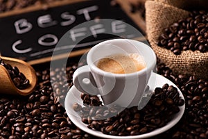 Coffee cup over dark roasted coffee beans