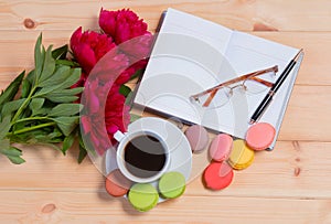 Coffee cup, pen, glasses, opened organizer and red peonies