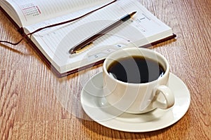 Coffee cup, pen, opened organizer