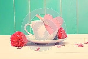 Coffee cup with pink heart tag and carnations