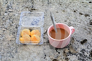 Coffee cup pink plastic and cream puffs in box on the Cement floor old with copy space