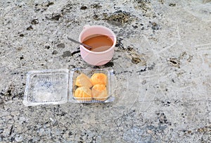 Coffee cup pink plastic and cream puffs in box on the Cement floor old with copy space