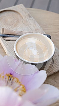 Coffee cup with pion. Cappuccino or latte on wooden table angle view photo
