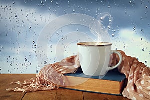 coffee cup on a rainy day over wooden table and window with rain