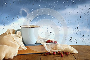 coffee cup on a rainy day over wooden table and window with rain