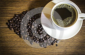 Coffee cup and roasted coffee beans on wooden