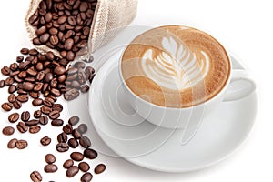 Coffee cup of rosetta latte art with coffee beans beside, on white background isolated