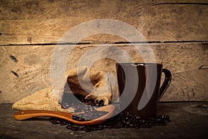 Coffee cup sack scoop of coffee beans on the old wooden floor.