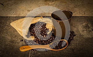 Coffee cup sack scoop of coffee beans on the old wooden floor.