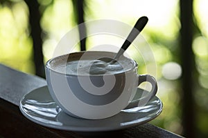Coffee cup and saucer,that the coffee in the cup on a wooden table  and nature  green background