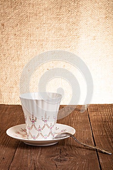 Coffee cup and saucer on a old wooden table. Burlap background