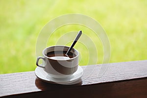 Coffee cup with saucer, on wood panel with defocus green grass lawn background