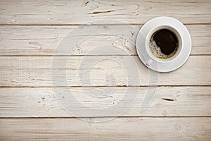 Coffee cup with saucer on wooden planks background, top view