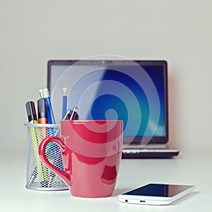 Coffee cup with smart phone on office desk