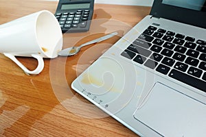 Coffee Cup spill out on Keyboard Laptop computer and smartphone on wooden floor