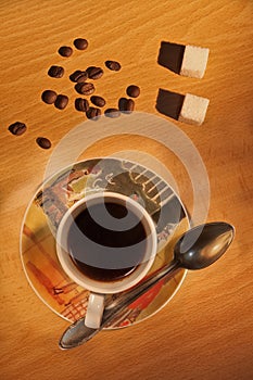 Coffee cup, spoon and coffee beans on a wooden table