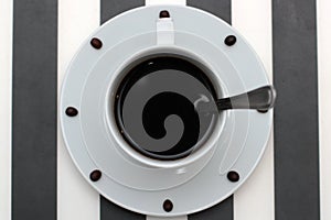 Coffee cup with spoon on saucer and coffee beans against white background forming clock dial. View from above. Coffee as symbol of