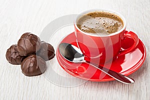 Coffee in cup, spoon on saucer, heap of chocolate candy