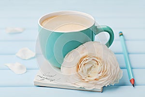 Coffee cup with spring flower and notes good morning on blue rustic background, breakfast