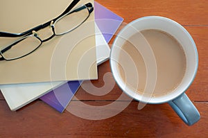 Coffee cup and stack book glasses on red wood table