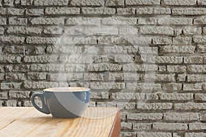 Coffee cup with stream of vapour against white brick wall background.