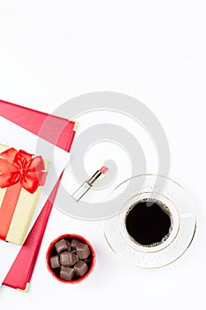 Coffee cup, sweets, lipstick, heart shape and giftbox on white background. Women`s Day concept flat lay.