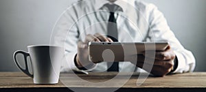 Coffee cup on table. Businessman using white digital tablet