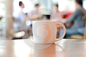 Coffee cup on the table with people in coffee shop as blur background