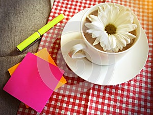 Coffee cup on table with white daisy