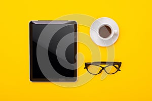 Coffee Cup, tablet and glasses isolated on yellow background