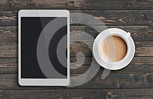 Coffee cup and tablet pc similar to ipad on dark wooden table top view photo