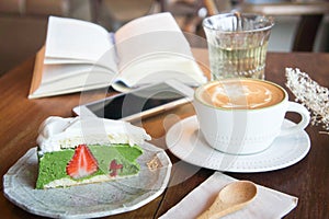 Coffee cup and tasty cake relax time book and mobile phone on ta